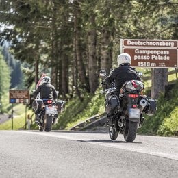 Pischadù-Klettersteig in Südtirol Drei Motorradfahrer fahren am Gampenpass in den Bergen vorbei