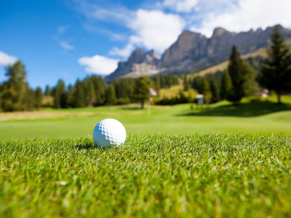 The mountain beast for golfers Palla da golf sull'erba con montagne e cielo blu sullo sfondo