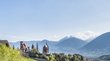 Hotels in Schenna: Traumziel für Südtirol-Reisende Landschaft mit Schloss, Kirche und Bergen unter blauem Himmel