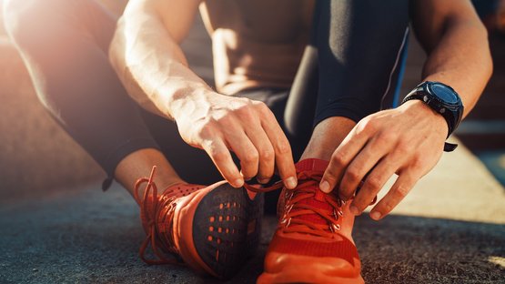 Rundstrecke M - Verdins Person bindet Laufschuhe an beim Training im Freien