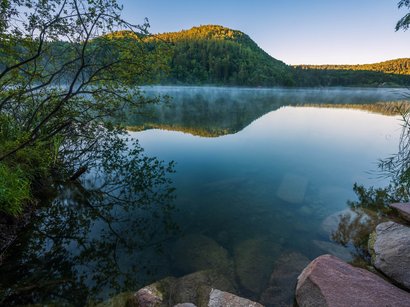 I laghi dell‘Alto Adige: meraviglie della natura Montagna e alberi riflessi in un lago calmo al mattino