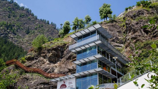 Il MuseoAltaPassiria di Moso in Passiria Centro visitatori moderno davanti a montagna rocciosa con cielo blu