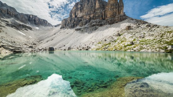 Lo splendido Lago Pisciadù nel Gruppo di Sella Lago alpino limpido turchese con rocce e cime ripide sotto un cielo nuvoloso