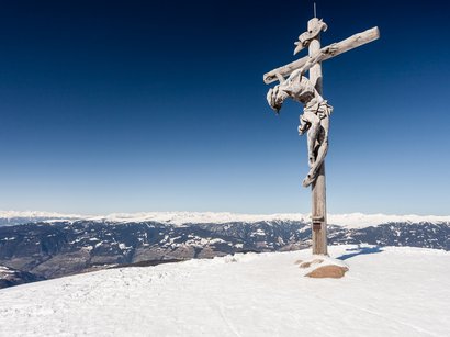 Sole, montagna, Alpe di Siusi! Croce di legno con figura di Gesù su montagna innevata con Alpi sullo sfondo