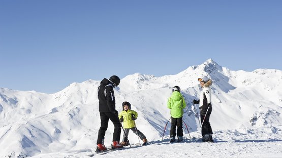 Schneespaß im Winterwunderland Watles Familie beim Skifahren auf verschneitem Berg mit klarem Himmel