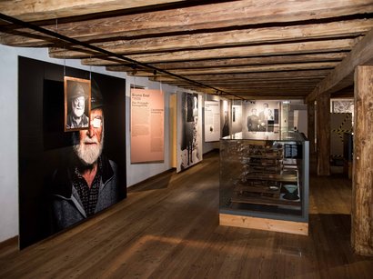 Bunker Museum Toblach Ausstellungsraum mit Holzdecke, Porträtfotos und historischen Exponaten