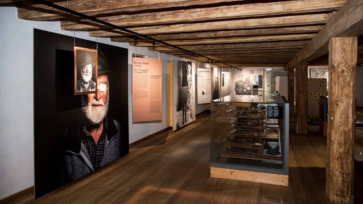 Das Bergbaumuseum in Steinhaus Ausstellungsraum mit Holzdecke, Porträtfotos und historischen Exponaten