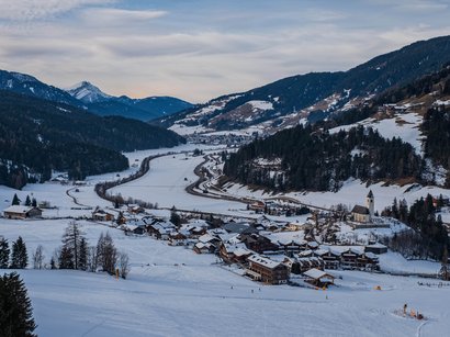 Rodelbahn Molignon Verschneites Bergdorf in einem Tal mit Bergen im Hintergrund