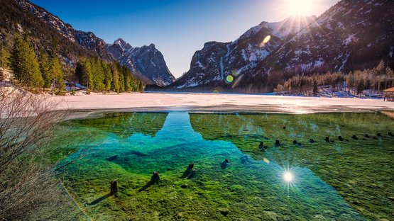 Lago balneabile tra due parchi naturali Lago limpido con montagne e sole in un freddo giorno d'inverno