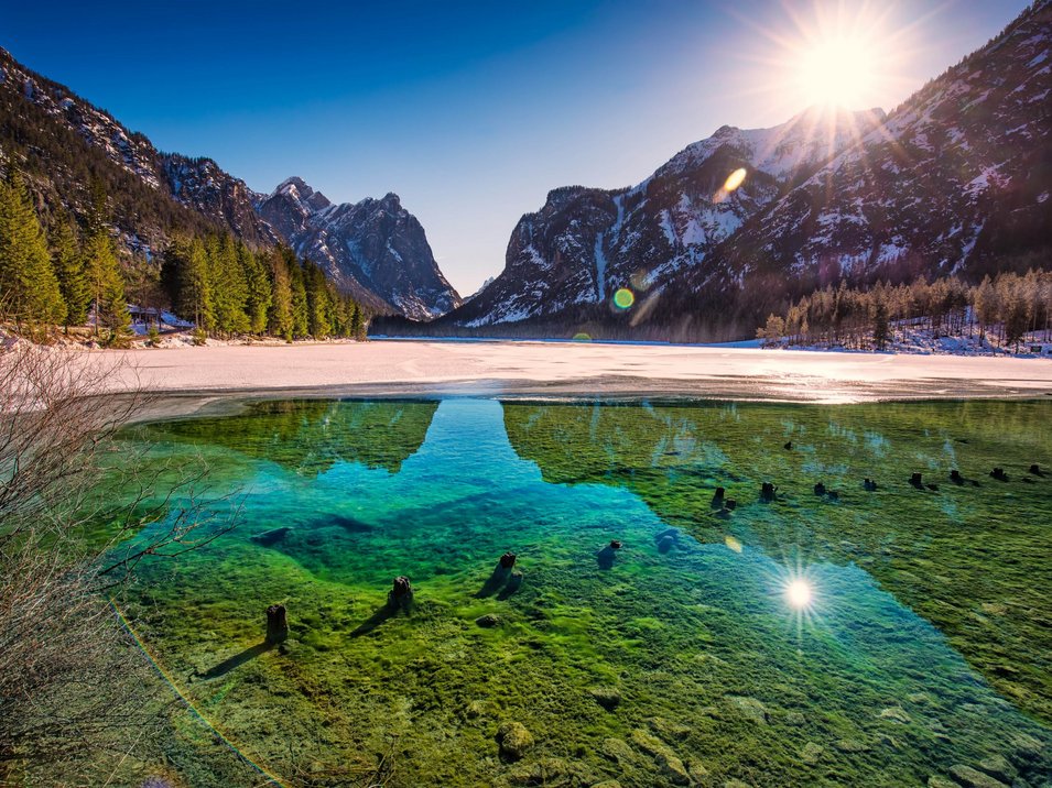 Lago balneabile tra due parchi naturali Lago limpido con montagne e sole in un freddo giorno d'inverno