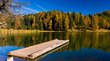 Lago di Santa Maria: che pace! Pontile di legno su lago calmo con foresta autunnale e cielo blu sullo sfondo