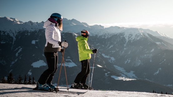 Traumhafte Skiabenteuer in Sterzing Zwei Skifahrer stehen auf verschneitem Hang mit Bergpanorama bei Sonnenuntergang