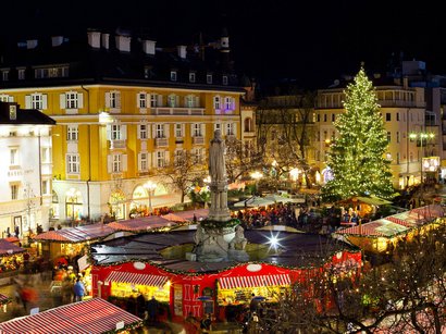 Der Mendelpass Weihnachtsmarkt mit beleuchtetem Baum und Marktständen in einer Stadt bei Nacht