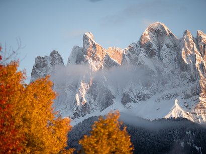 Traumhafte Skiabenteuer in Sterzing Schneebedeckte Berge mit herbstlich bunten Bäumen und leichtem Nebel