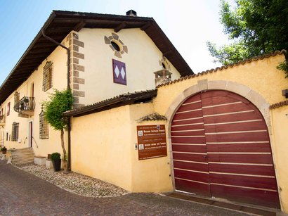 Cinè Museum a Bolzano Edificio storico con grande porta rossa e cartelli su strada lastricata