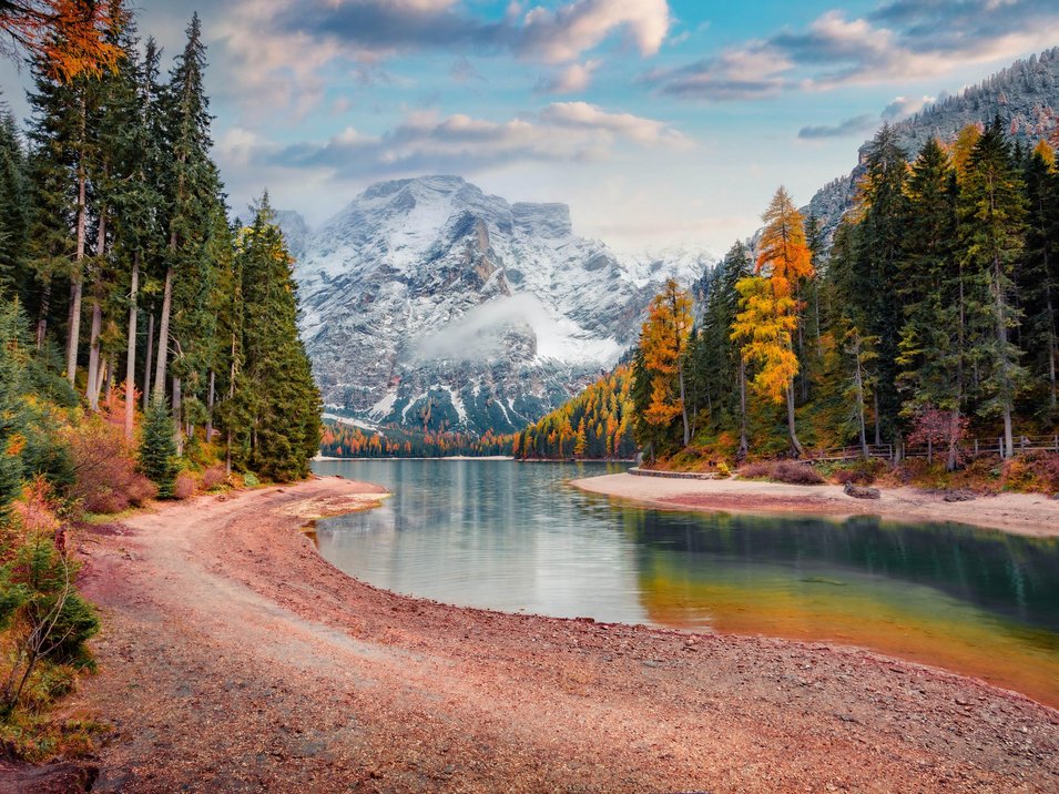 Scopri il Passo Furcia a 1789 m Lago di montagna autunnale con alberi colorati e cime innevate sullo sfondo