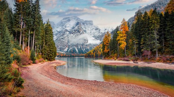 Scopri il Passo Furcia a 1789 m Lago di montagna autunnale con alberi colorati e cime innevate sullo sfondo