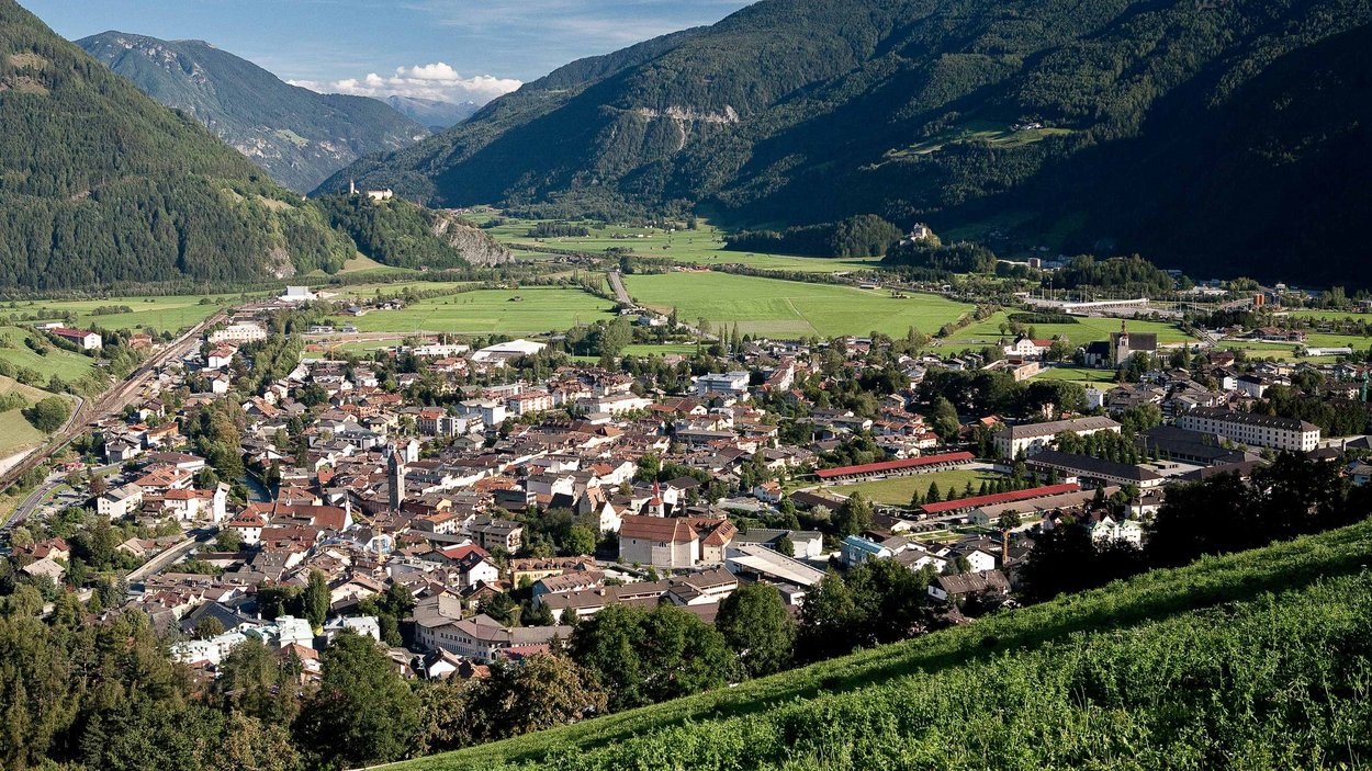 Die Hotels in Sterzing versprechen wunderbare Tage Blick auf eine Stadt im Tal umgeben von Bergen und grünen Wiesen bei klarem Himmel