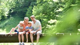 Hotel Kronblick Glückliche Familie mit zwei Kindern sitzt auf einer Brücke in der Natur