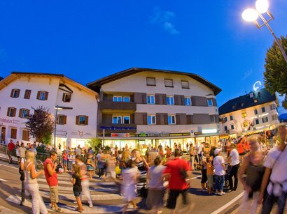 Il mercatino di Natale di Bolzano Folla di persone durante un evento serale in un quartiere animato con edifici illuminati