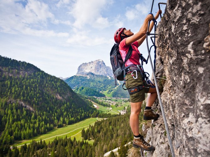 Arrampicata in Alto Adige: si sale in alta quota! Donna scala una parete rocciosa con casco e attrezzatura in montagna