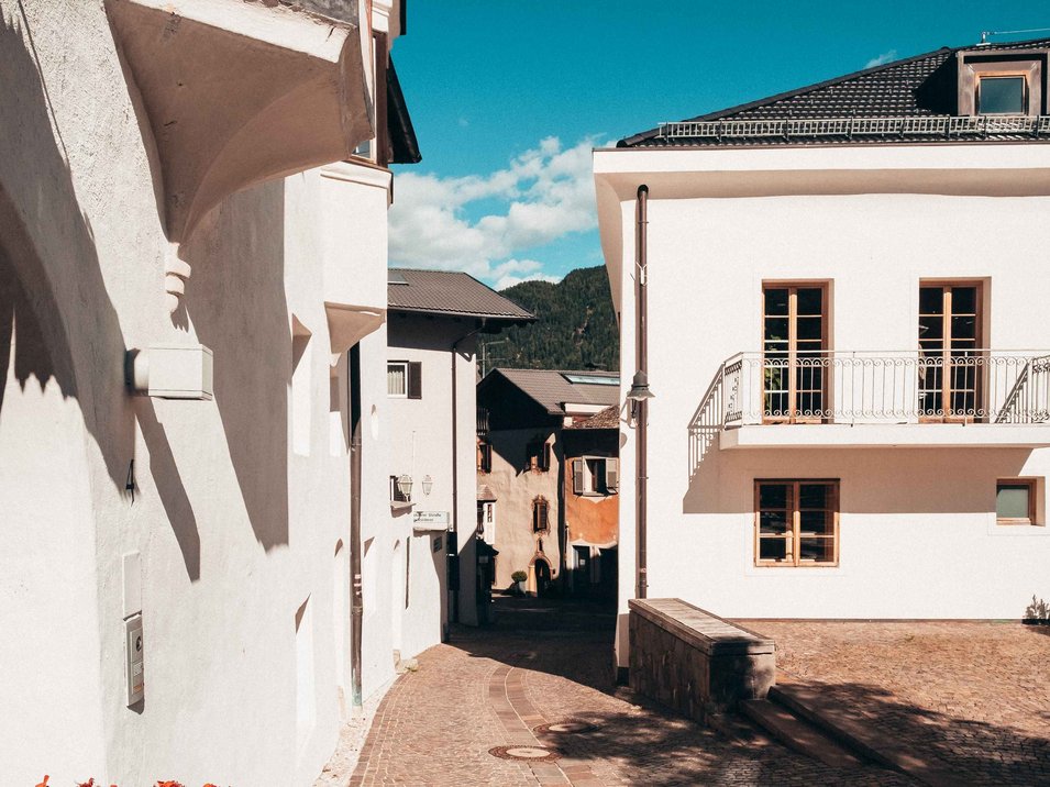 Ihre Hotels in Mühlbach mit Stil Pflasterstraße in einem sonnigen historischen Dorf mit weißen Häusern und blauen Himmel