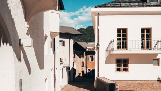 Ihre Hotels in Mühlbach mit Stil Pflasterstraße in einem sonnigen historischen Dorf mit weißen Häusern und blauen Himmel