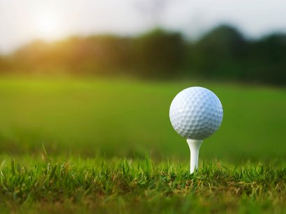 Der Heiligkreuzkofel Golfball auf Tee im grünen Gras eines Golfplatzes bei Sonnenlicht