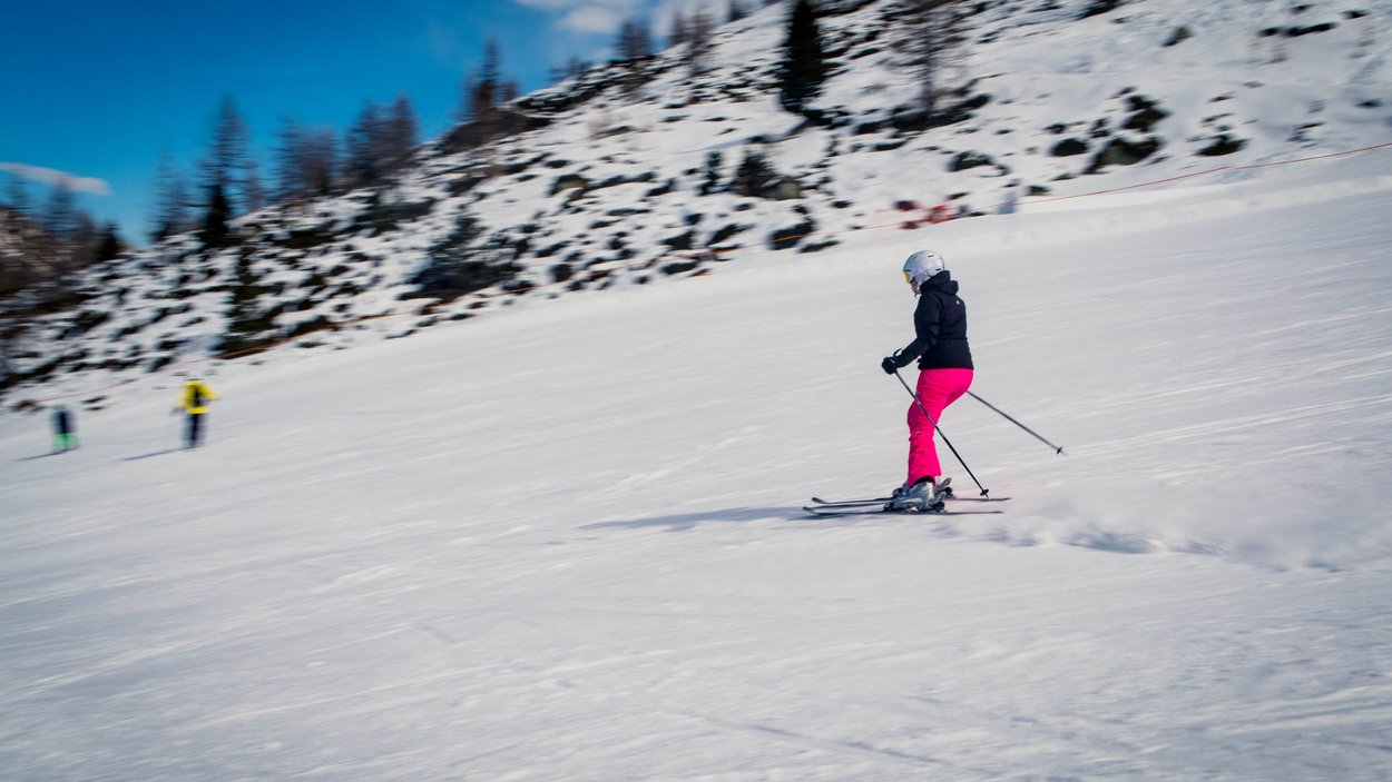 Skispaß im urigen Pfelders Person fährt Ski auf schneebedecktem Hang unter blauem Himmel