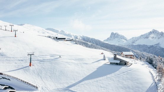 Traumhafte Winterauszeit in Brixen Verschneite Berglandschaft mit Skilift und Berghütten unter blauem Himmel
