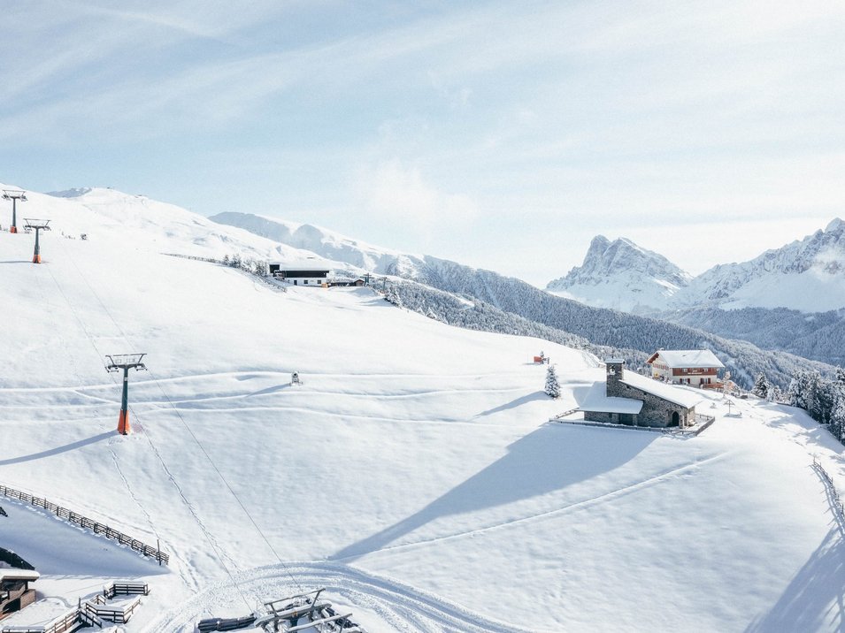 La magia dell‘inverno di Bressanone Paesaggio montano innevato con impianto di risalita e baite sotto un cielo blu