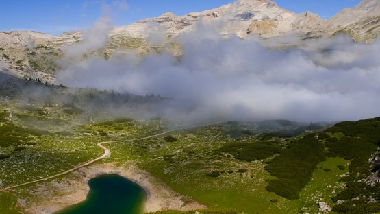 Der Limosee im Gadertal Berglandschaft mit kleinem See und Nebel unter blauem Himmel