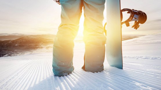 Winterspaß am Reschenpass Person steht auf verschneitem Hang mit Snowboard bei Sonnenuntergang