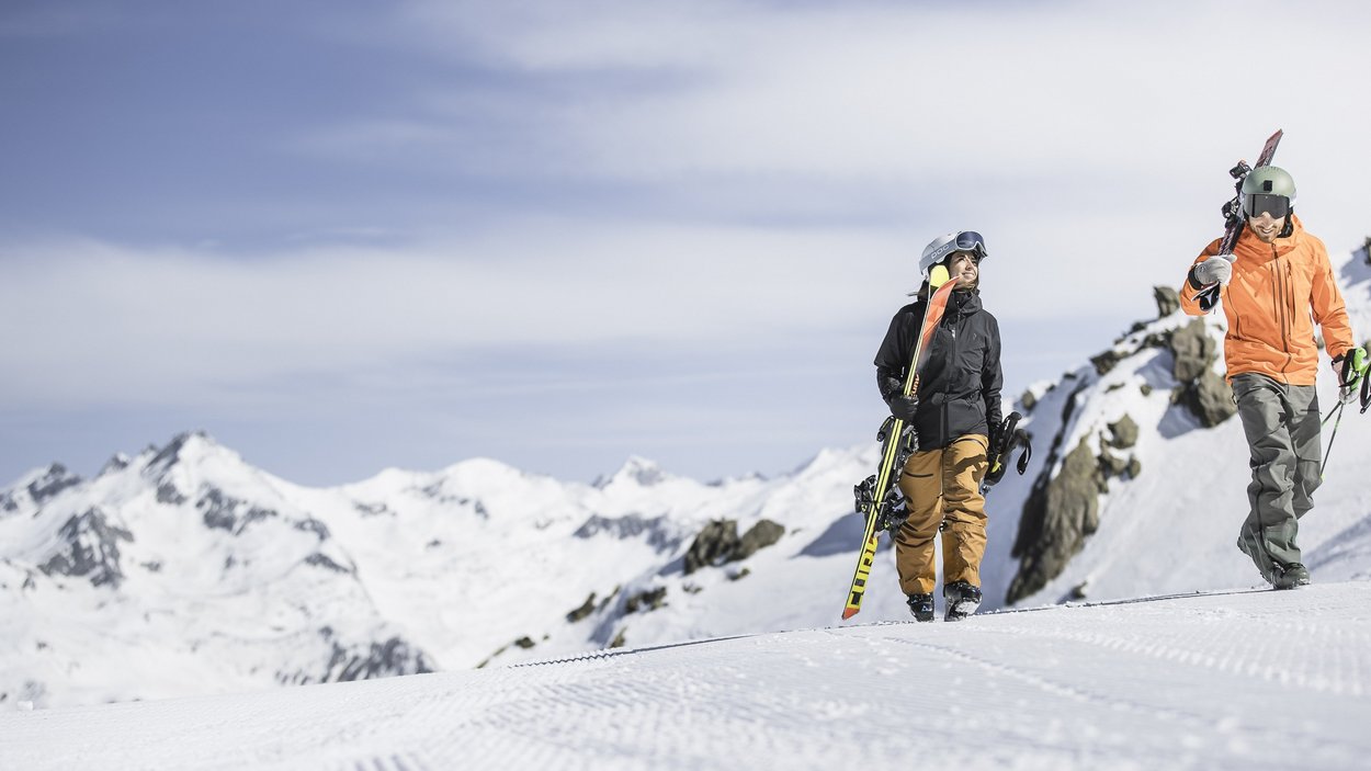 Klausberg in Valle Aurina: divertirsi sulla neve in Alto Adige Due sciatori con attrezzatura che camminano su una montagna innevata con cielo sereno