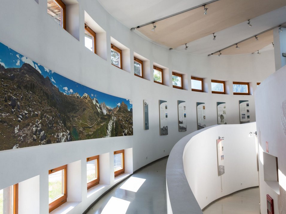 Centro visite Fanes-Senes-Braies Interno di un museo curvo con panorama montano e pannelli espositivi