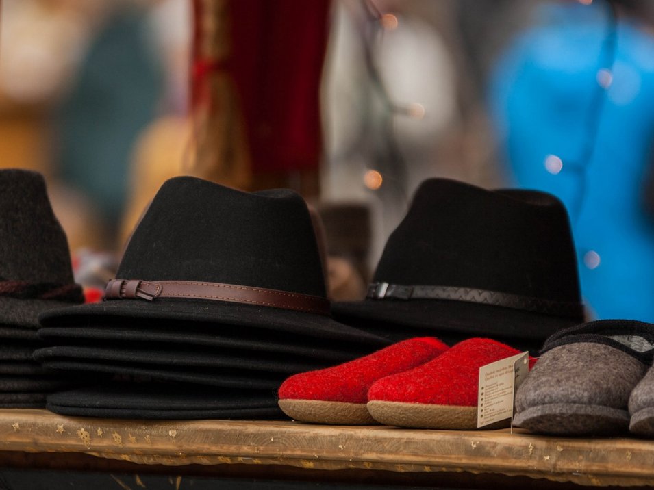 Der Weihnachtsmarkt in Brixen Verschiedene Filzhüte und Hausschuhe auf einem Marktstand