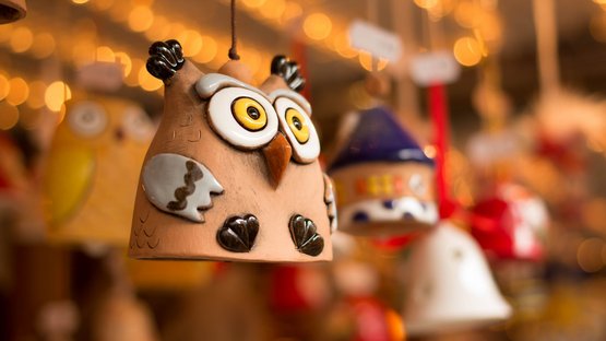 Il mercatino di Natale di Bolzano Figura di gufo in terracotta appesa davanti a uno sfondo sfocato con luci