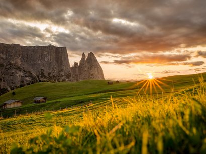 Il regno di Re Laurino Tramonto su colline verdi, rocce e baite di legno nelle Alpi