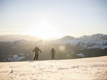 Hotel a Val Sarentino in Alto Adige Due sciatori scendono in montagna innevata al tramonto