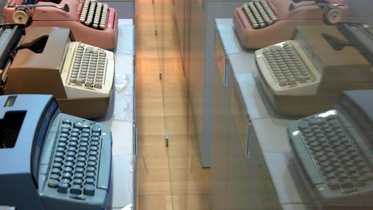Il museo della macchina da scrivere a Parcines Tre macchine da scrivere vintage blu, beige e rosa su un tavolo con riflesso