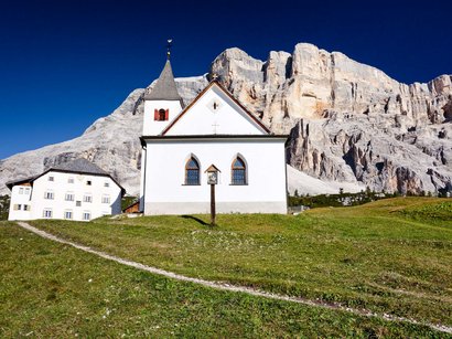 Il regno di Re Laurino Cappella bianca davanti a parete rocciosa sotto un cielo blu nelle Alpi