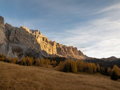 Hotel a La Villa in Val Badia Catena montuosa rocciosa con foresta e prato autunnale sotto cielo blu