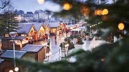 Ihre Hotels in Meran in Südtirol: Hotels im Meraner Land Weihnachtsmarkt mit Holzhütten und warmen Lichtern an einem regnerischen Abend