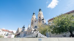 Hotels Eisacktal, Südtirol: Hotels in Brixen, Klausen … Kirchturm mit zwei Uhren in einer historischen Stadt unter blauem Himmel