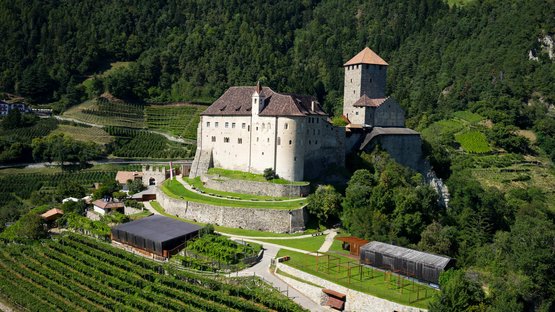Kuenser Erdpyramiden Burg mit Weinbergen und Wäldern auf einem Hügel bei Sonnenschein