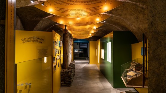 Das Vintschger Museum Innenbereich eines Museums mit gelben und grünen Ausstellungswänden und Informationsleuchten