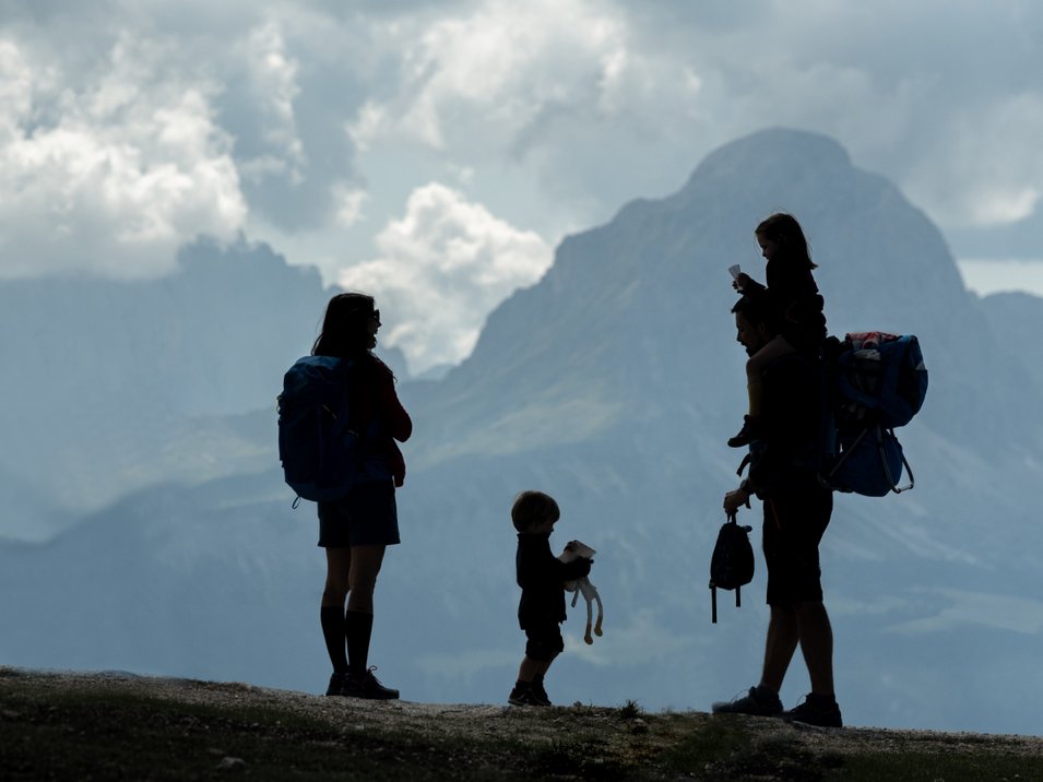 Hörspielwanderungen am Latemar Silhouetten einer Familie beim Wandern mit Bergkulisse und Wolken
