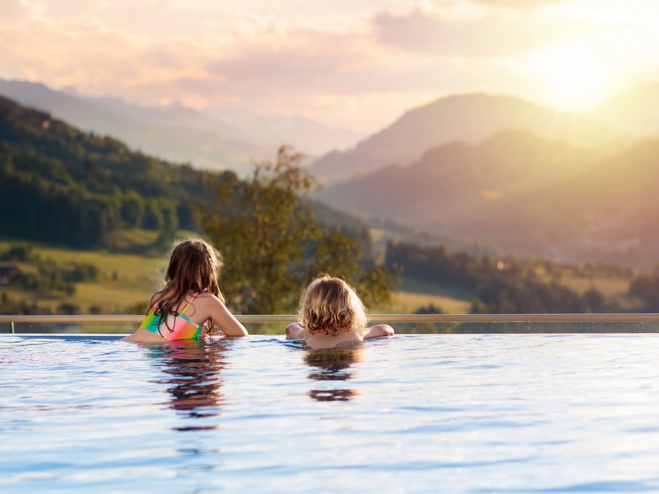 Hotels mit Pool in Südtirol Zwei Kinder im Pool mit Blick auf sonnige Berge und Tal