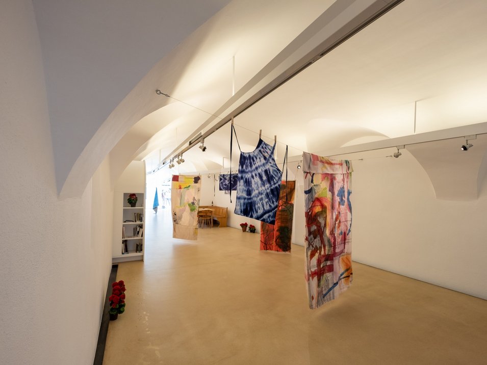 Galleria Civica di Bressanone Installazione artistica con tessuti colorati appesi in una stanza bianca
