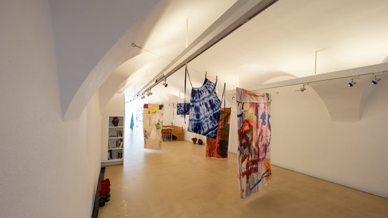 Die Stadtgalerie Brixen Kunstinstallation mit bunten Textilien, die in einem weißen Raum hängen